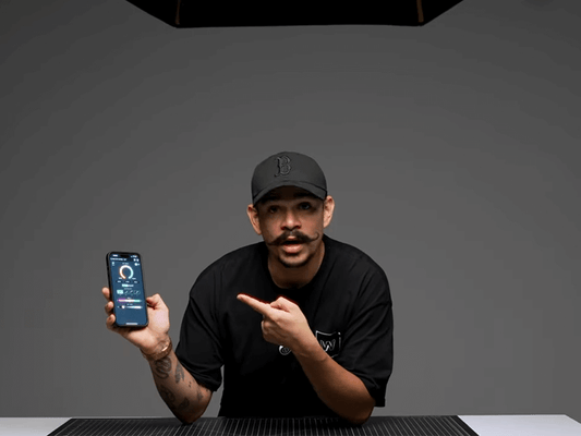 A content creator pointing to the GVM smartphone app for remote control and adjustment of professional studio lighting.