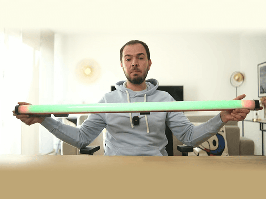 A content creator holding the 1.2-meter GVM-BD45R wand light with a vibrant green and pink gradient, showcasing the ultimate Video Wand Light for elevating your led light stick photography and YouTube studio setup.